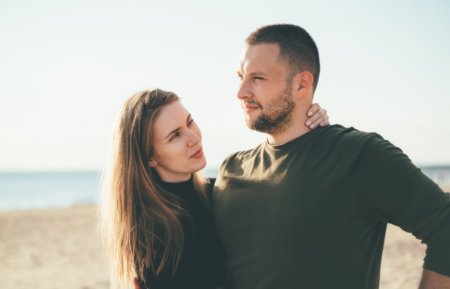 Kobieta i mężczyzna stojący razem na plaży, patrzący w przyszłość – spokojna, wspierająca atmosfera.