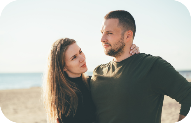 Para stojąca na plaży, patrząca w przyszłość i obejmująca się