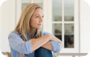 Kobieta w średnim wieku siedząca z zamyśleniem, patrząca w dal